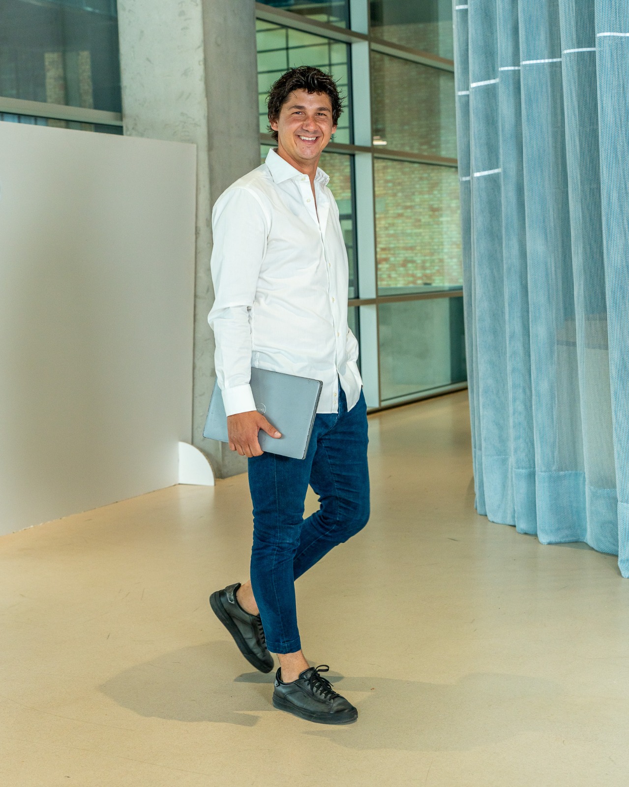 Il fondatore di I-WIN cammina sorridendo con il portatile sottobraccio